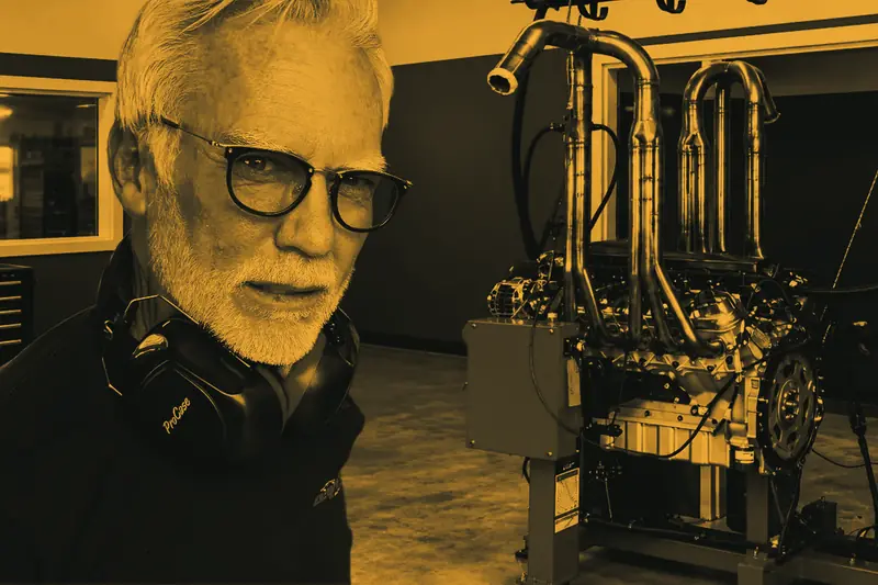 Dave Bell, hearing protection around his neck, in front of an engine mounted on a red dyno rig